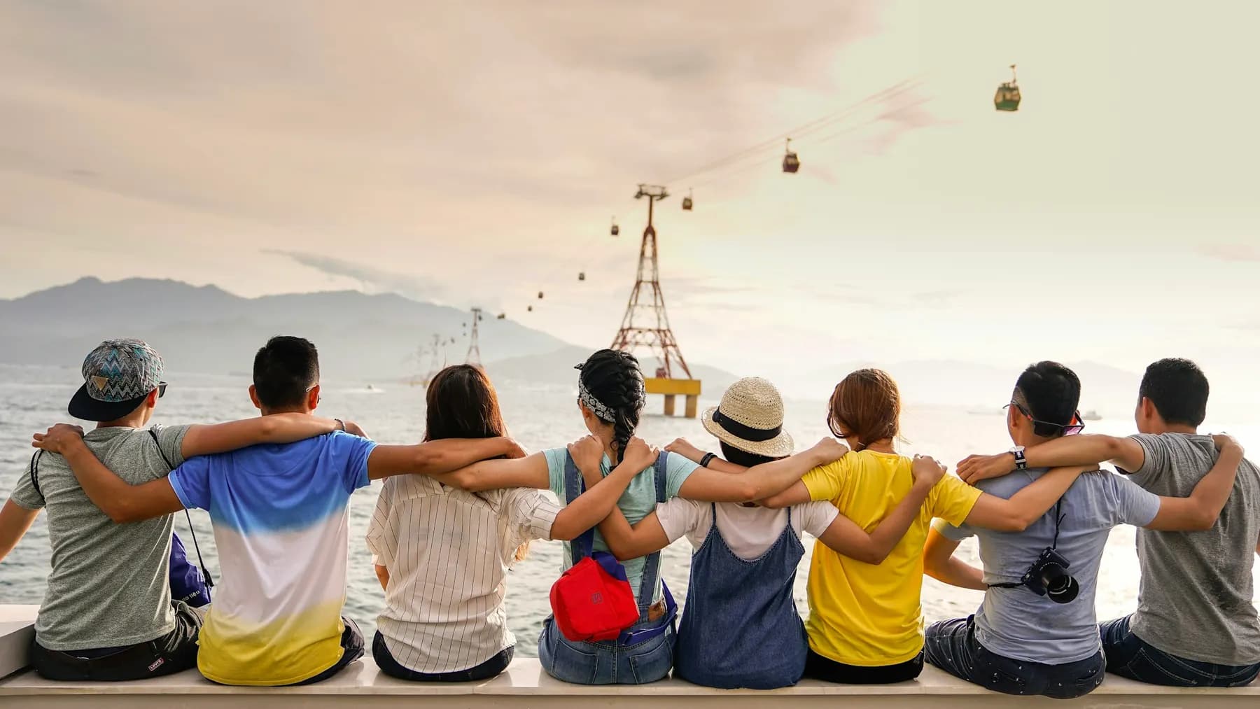 A group of friends sitting arm in arm, looking out over the water
