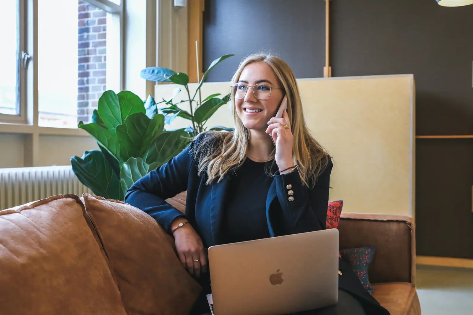 A woman on a phone call, smiling, with her laptop open